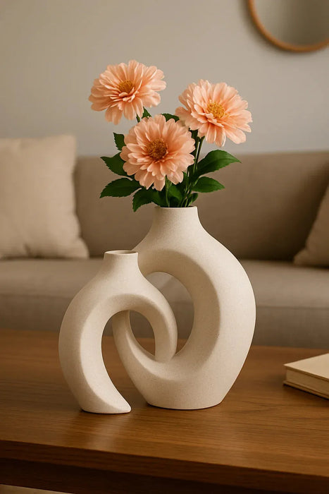 Minimalist round ceramic vase set with abstract sculptural shapes, displayed with colorful fresh flowers on a wooden patio table in a natural outdoor setting
